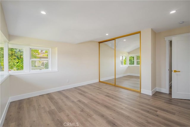 unfurnished bedroom with baseboards, vaulted ceiling, wood finished floors, and recessed lighting