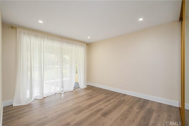 unfurnished room with baseboards, wood finished floors, and recessed lighting