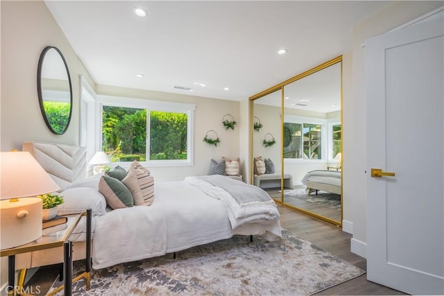 bedroom with a closet, visible vents, wood finished floors, and recessed lighting