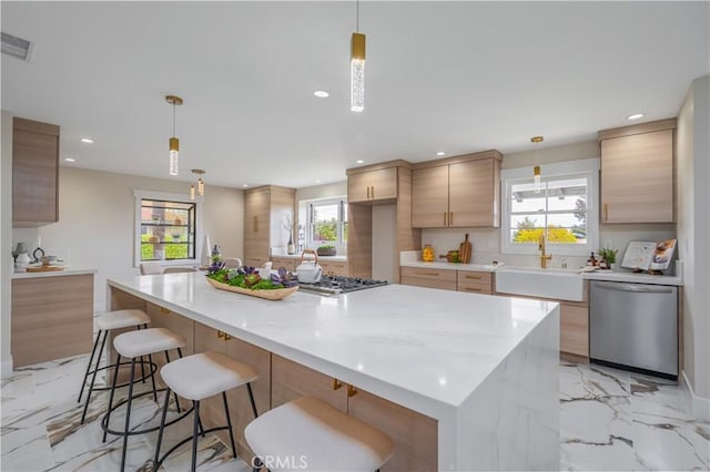 kitchen featuring marble finish floor, stainless steel appliances, hanging light fixtures, and a sink