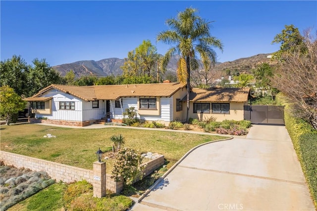 ranch-style home with driveway, a front yard, and a mountain view