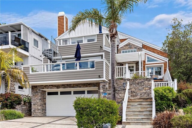 1020 La Mirada St, Laguna Beach, CA 92651 - back of house featuring an attached garage, stone siding, concrete driveway, stairway, and a chimney