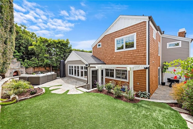 rear view of house featuring a patio, an outdoor living space with a fireplace, a lawn, and board and batten siding