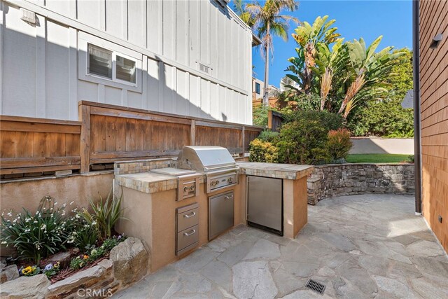 view of patio / terrace featuring an outdoor kitchen, fence, and grilling area