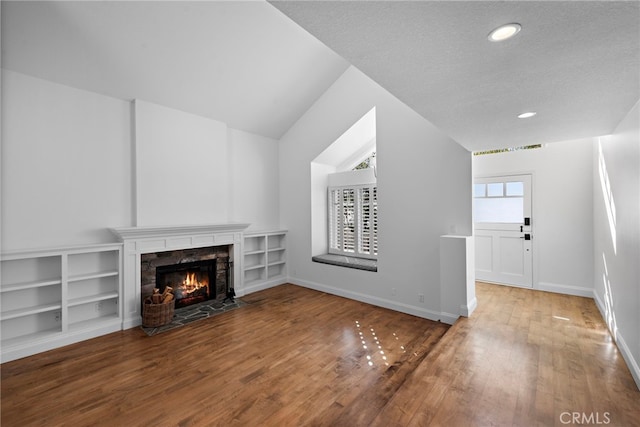 unfurnished living room with wood finished floors, baseboards, recessed lighting, a tile fireplace, and vaulted ceiling