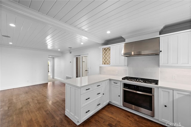 kitchen featuring wall chimney range hood, stainless steel appliances, a peninsula, white cabinets, and light countertops