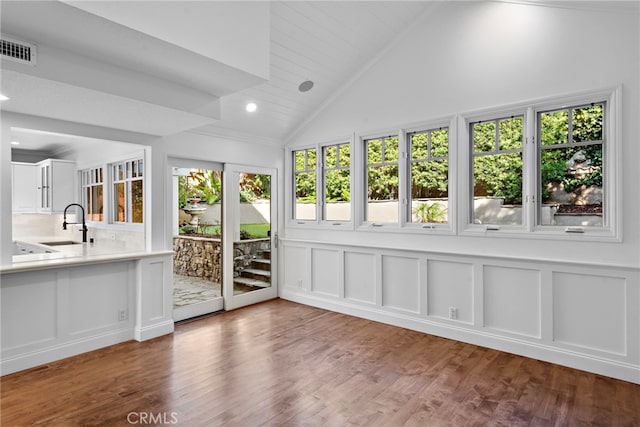 unfurnished sunroom featuring a sink, visible vents, and lofted ceiling