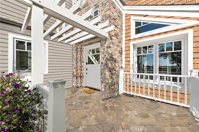 property entrance featuring stone siding and a patio