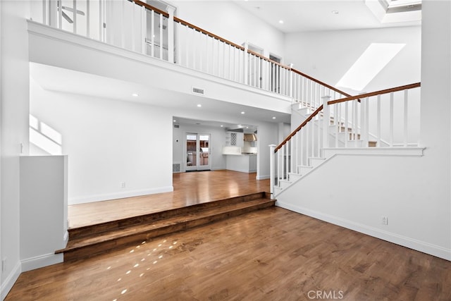 interior space with stairway, a high ceiling, visible vents, and wood finished floors