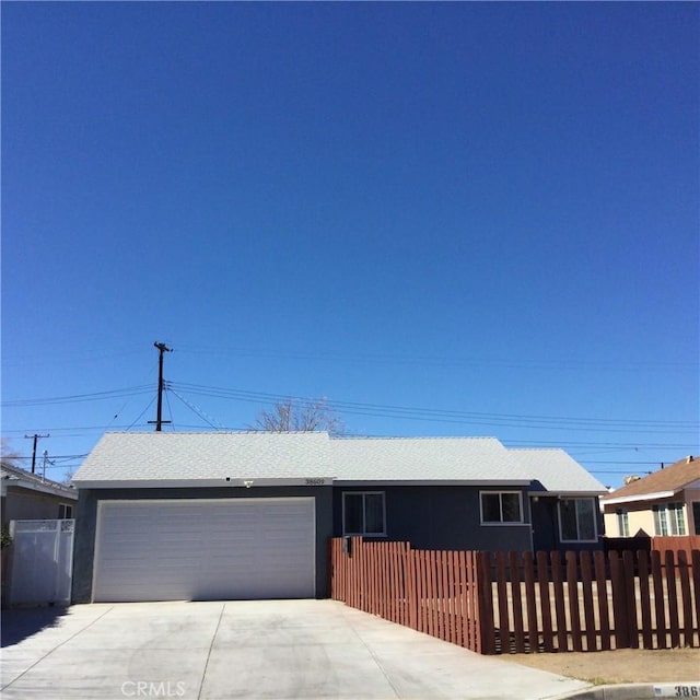 ranch-style home with a garage, concrete driveway, and a fenced front yard