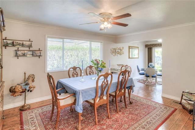 dining room with baseboards, wood finished floors, and crown molding