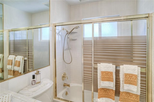 full bath with combined bath / shower with glass door, toilet, and a healthy amount of sunlight