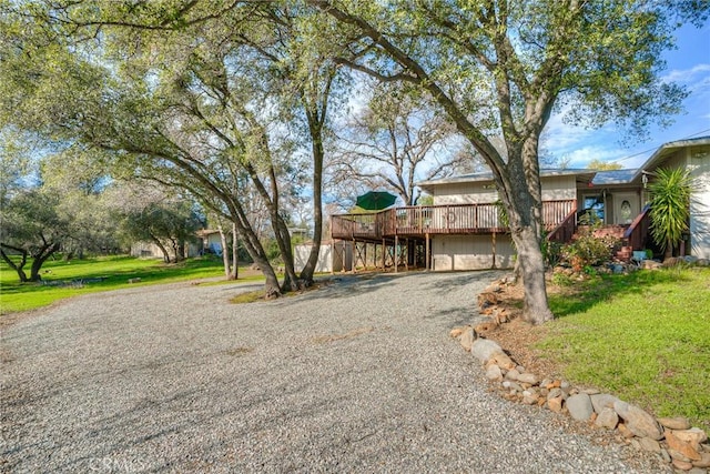 view of front of property featuring a deck, driveway, and a front yard