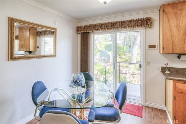 dining space featuring crown molding, light wood-style flooring, and baseboards