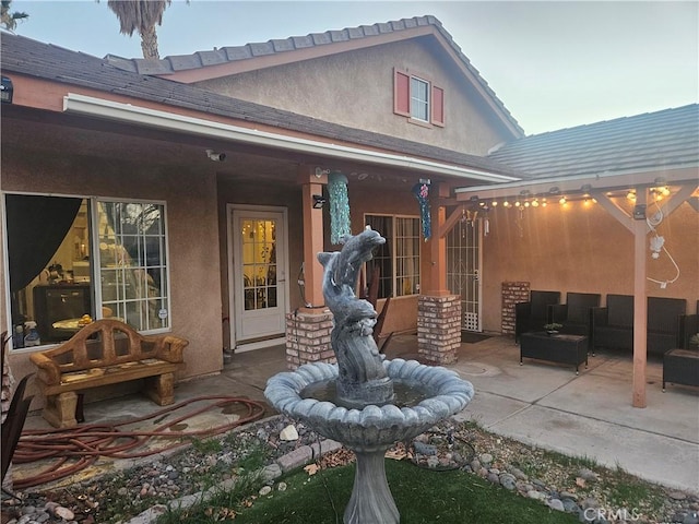 rear view of property featuring an outdoor hangout area, a patio, and stucco siding