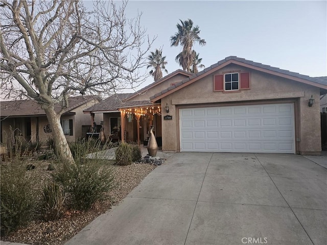 ranch-style house with driveway, an attached garage, and stucco siding