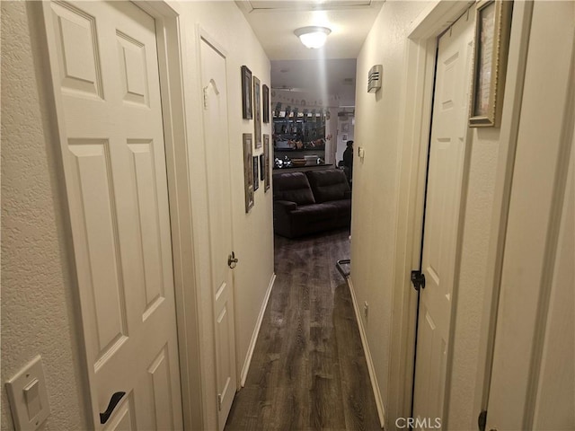 hallway with a textured wall and dark wood finished floors