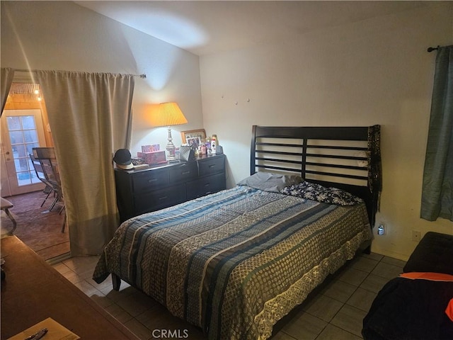 bedroom with dark tile patterned flooring and vaulted ceiling