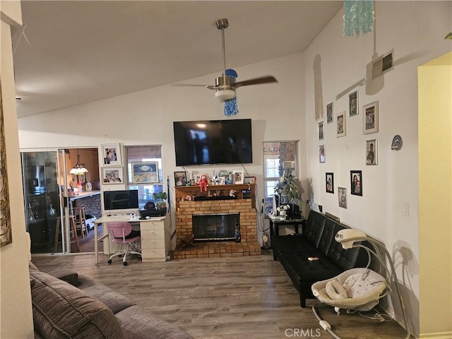 living area with lofted ceiling, a brick fireplace, ceiling fan, and wood finished floors