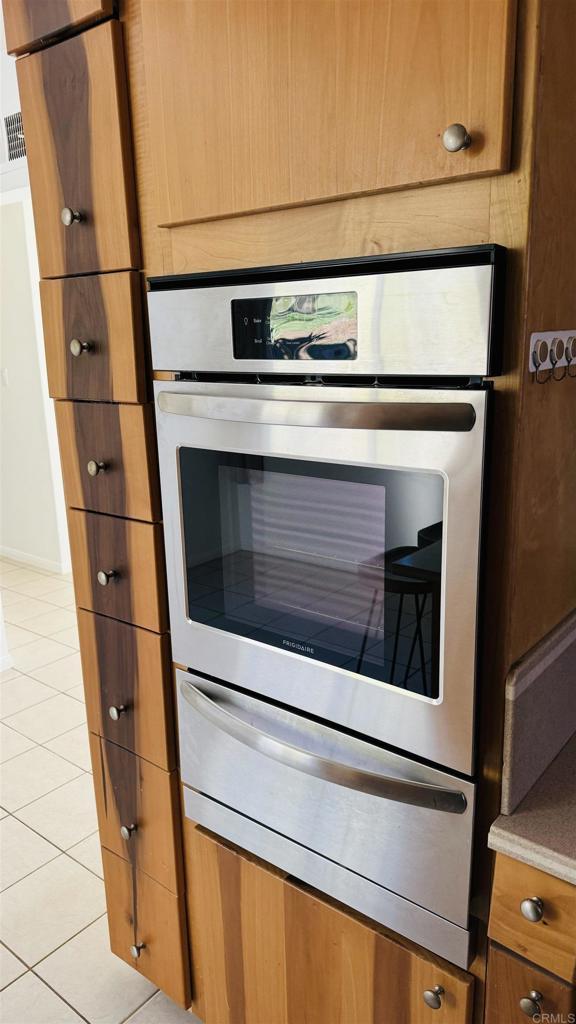 interior details with brown cabinetry, light countertops, and a warming drawer