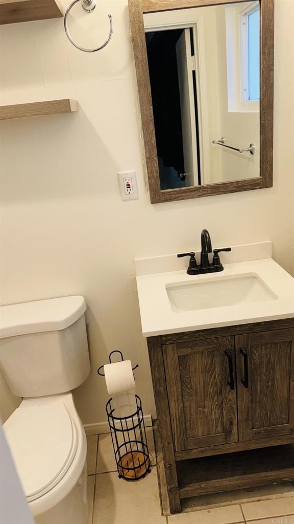 half bath with tile patterned flooring, vanity, and toilet