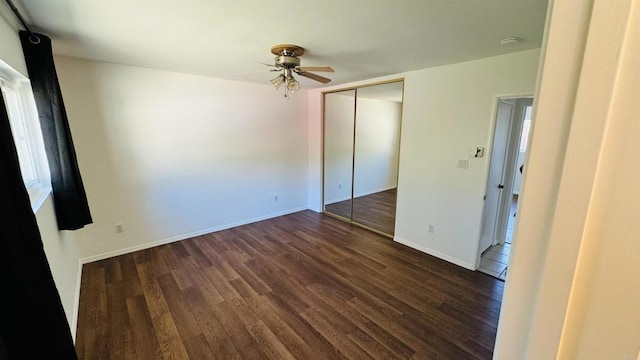 unfurnished bedroom with dark wood-style floors, ceiling fan, baseboards, and a closet