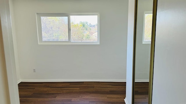 unfurnished room featuring baseboards and dark wood-style flooring