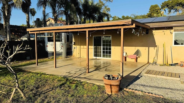 rear view of property with a patio area, fence, solar panels, and stucco siding