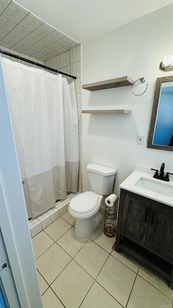 bathroom with a stall shower, vanity, toilet, and tile patterned floors