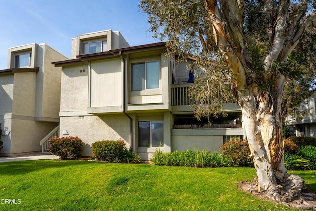 rear view of property with a lawn and stucco siding