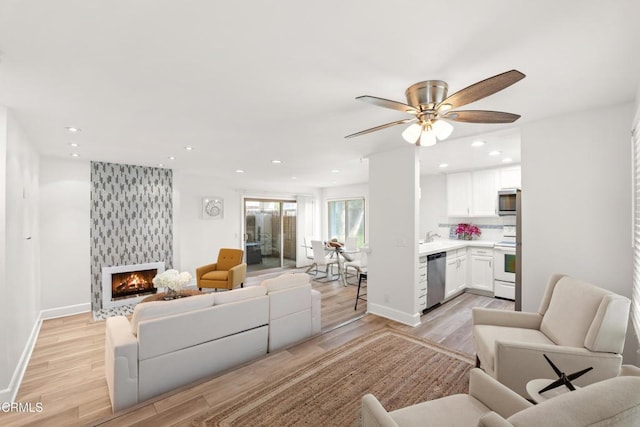 living area featuring recessed lighting, a fireplace, and light wood-style floors