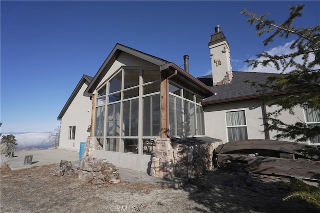 25841 Remington Ct, Tehachapi, CA 93561 - view of home's exterior featuring a sunroom, roof with shingles, a chimney, and stucco siding