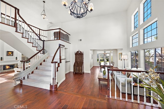 entryway with a healthy amount of sunlight, wood-type flooring, a glass covered fireplace, and a notable chandelier