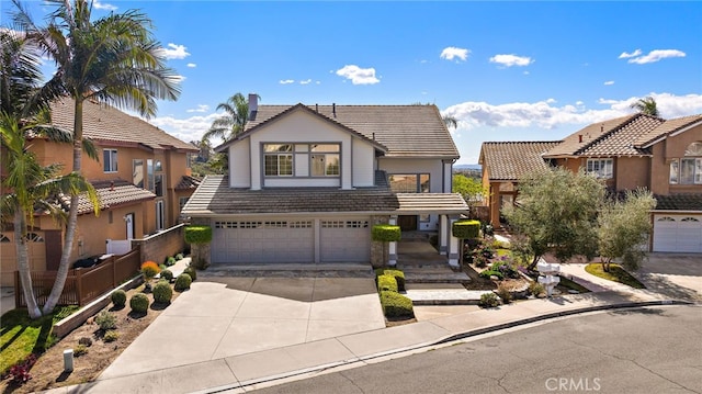 view of front of property with concrete driveway, a tiled roof, fence, and a garage