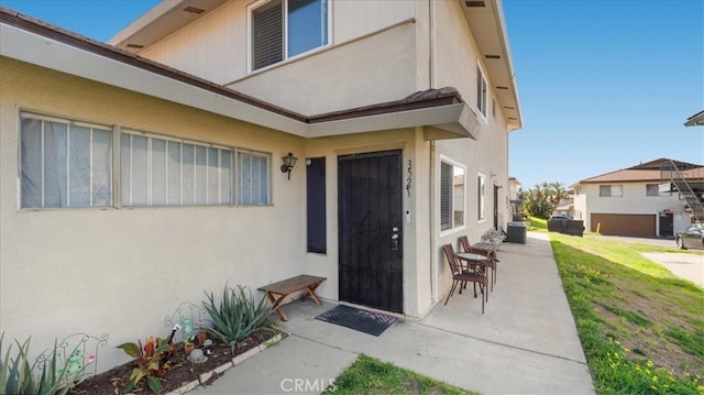 doorway to property with a patio, central AC unit, and stucco siding