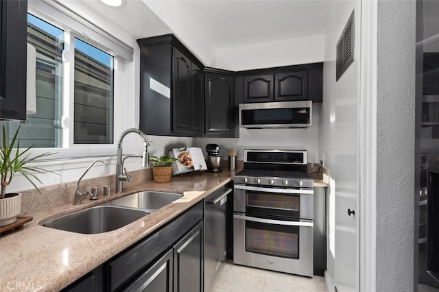 kitchen with light stone counters, a sink, visible vents, appliances with stainless steel finishes, and dark cabinetry