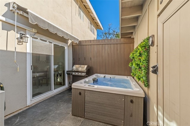 view of patio featuring area for grilling, fence, and a hot tub