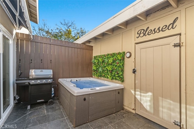 view of patio with fence, a grill, and a hot tub