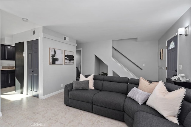 living room with stairway, visible vents, and baseboards