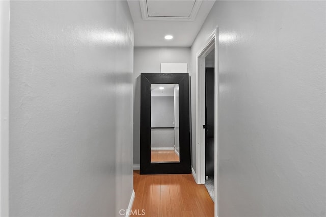 corridor featuring light wood-type flooring and baseboards