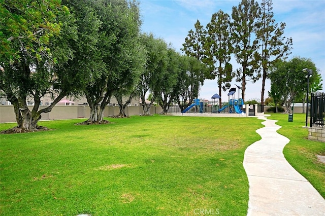 view of property's community with a yard, playground community, and fence