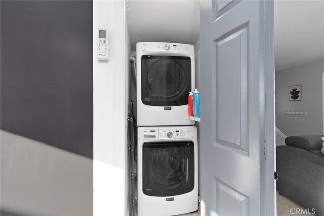 clothes washing area featuring stacked washer and dryer and laundry area