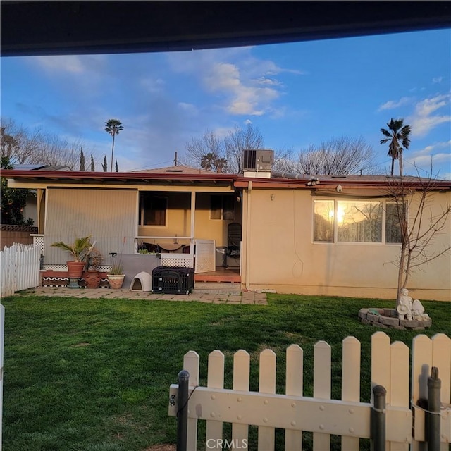 exterior space featuring a lawn, central AC, and fence