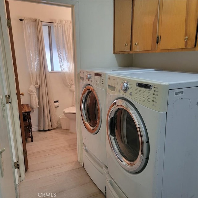 washroom with light wood-type flooring, cabinet space, and washing machine and dryer