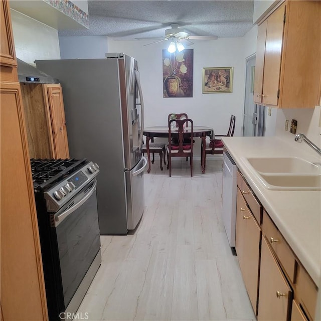 kitchen featuring stainless steel gas stove, a ceiling fan, a sink, a textured ceiling, and white dishwasher