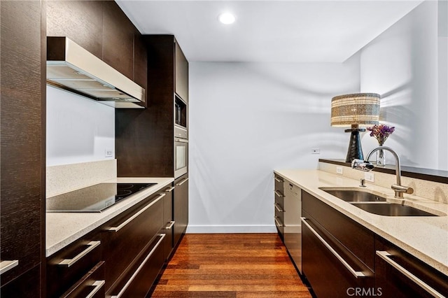 kitchen with dark wood finished floors, modern cabinets, light stone counters, black appliances, and a sink