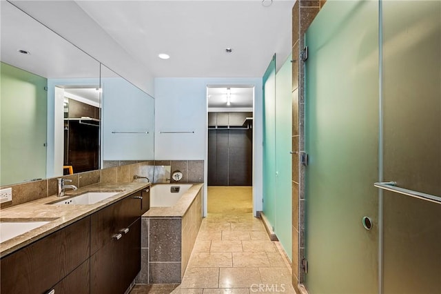 full bath featuring stone tile flooring, a sink, a shower stall, and a bath