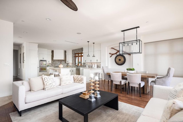 living area with light wood-type flooring, baseboards, and recessed lighting