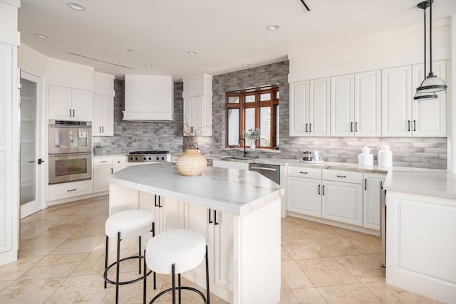 kitchen featuring a center island, pendant lighting, custom exhaust hood, stainless steel appliances, and white cabinetry