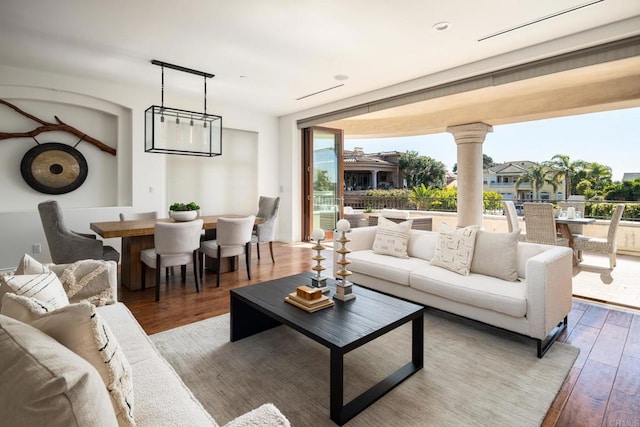 living area featuring decorative columns, a wall of windows, wood finished floors, and a wealth of natural light